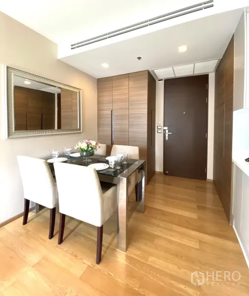 Condominium for rent in Ratchathewi, Bangkok - Bright dining area with glass-top table, upholstered chairs, built-in wood cabinetry and light wood floors in a Bangkok condo.