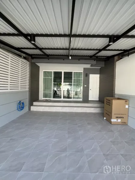 Townhouse for rent in Bang Kapi, Bangkok - Covered carport with tiled floor and sliding glass entry to the house.