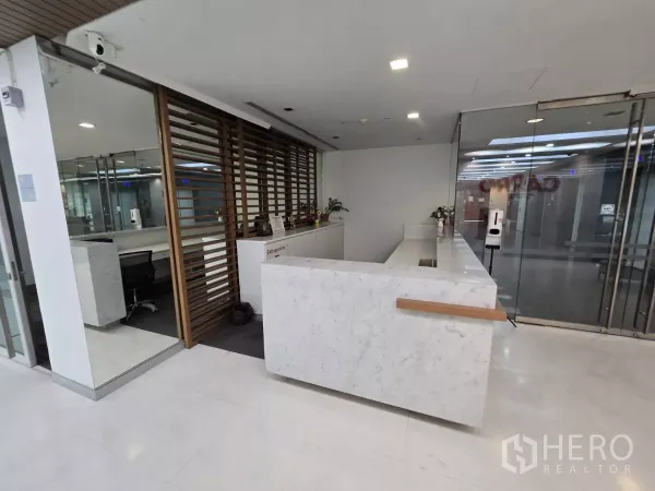 Office Space for rent in Watthana, Bangkok - Modern marble reception desk with glass doors and wood slat divider in a Bangkok office.