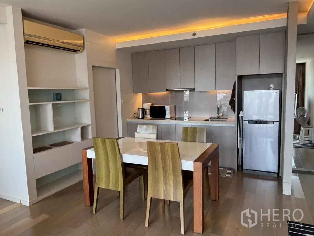 Condominium for sale in Watthana, Bangkok - Modern open kitchen with built-in cabinets, dining table, and full-size refrigerator.