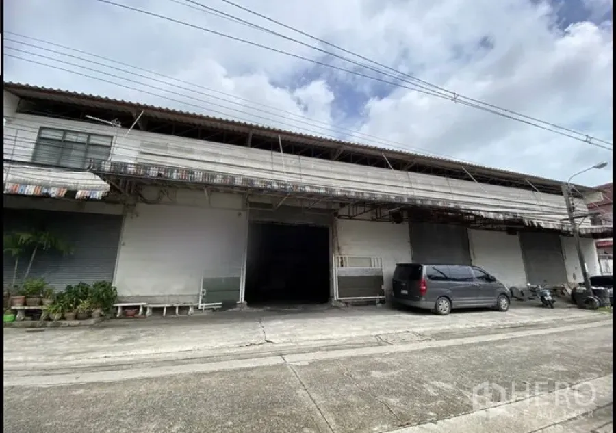 Warehouse for rent in Bang Khun Thian, Bangkok - Street-facing warehouse exterior in Bang Khun Thian with multiple roller shutters, covered loading bay, and parking area.