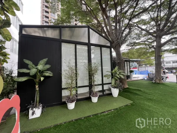 零售空间 出租在Watthana, Bangkok - 温室风独立小亭，通高落地窗，盆栽点缀，树荫下的人造草坪。