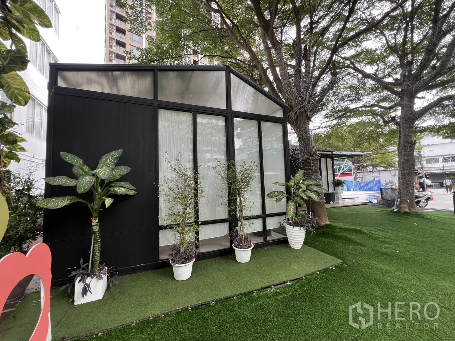 零售空间 出租在Watthana, Bangkok - 温室风独立小亭，通高落地窗，盆栽点缀，树荫下的人造草坪。