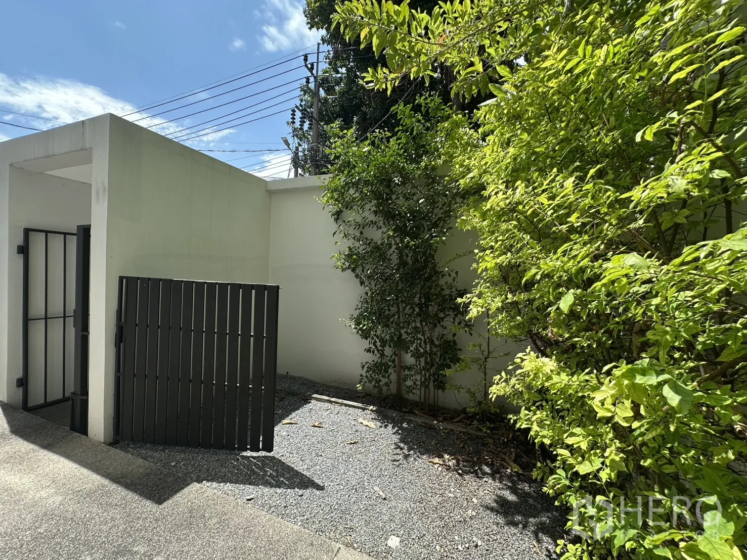 Home Office for rent in Phra Khanong, Bangkok - Small gravel courtyard with leafy greenery and a high boundary wall.