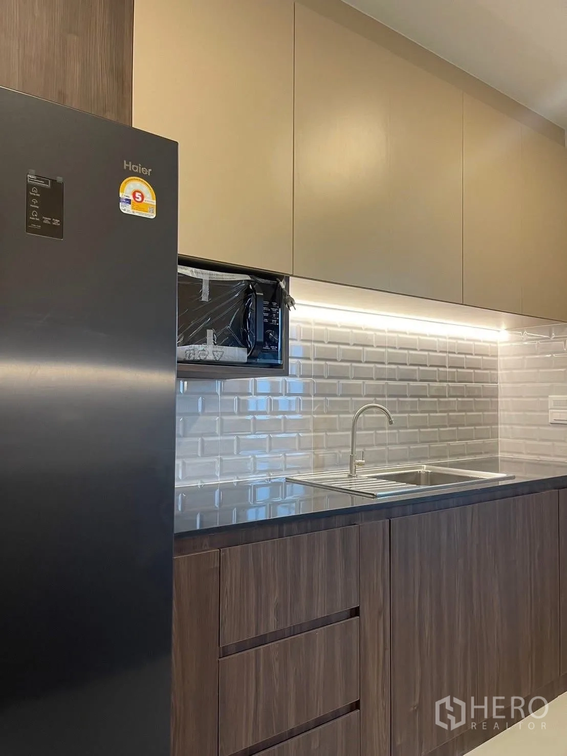 Detached House for rent in Bang Phli, Samut Prakan - Kitchen close-up showing refrigerator, microwave, storage and stainless sink.