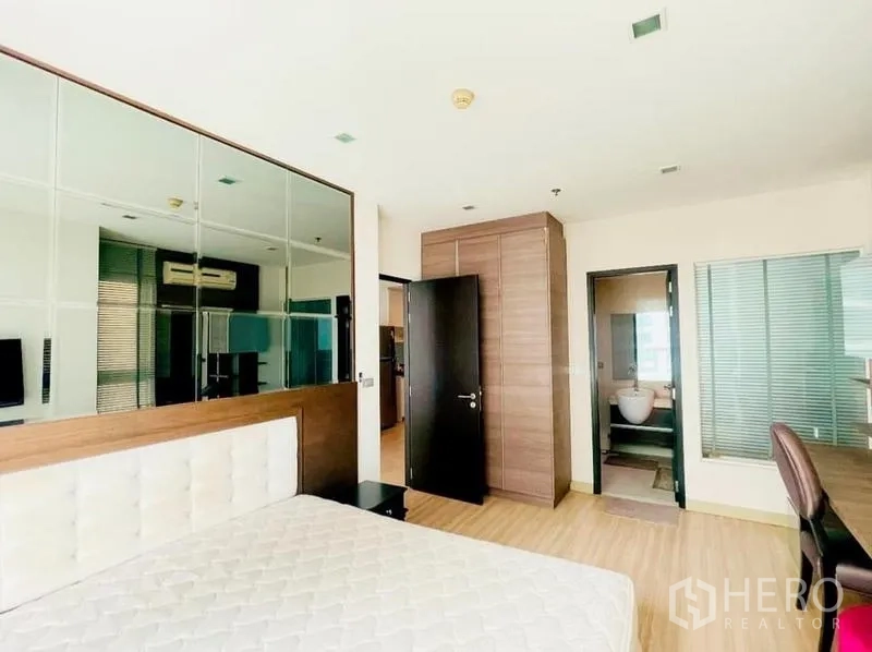 Condominium for rent - Master bedroom with bed, tall wardrobe, and door to the bathroom.