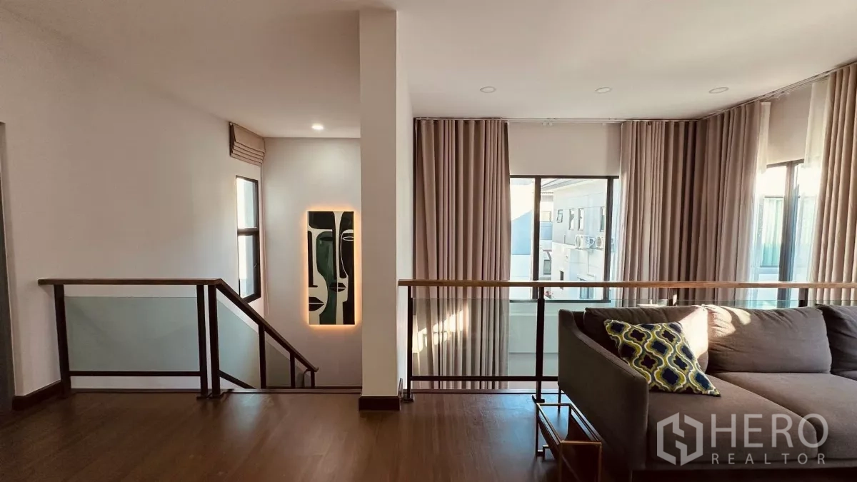 Detached House for rent in Bang Phli, Samut Prakan - Upstairs family lounge with an L‑shaped sofa, glass balustrade and tall windows.