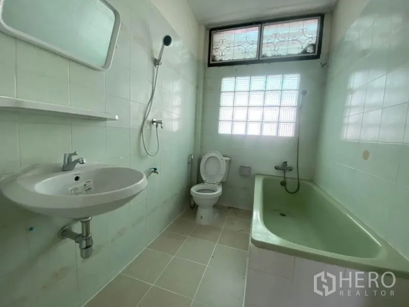 联排别墅 出租在Watthana, Bangkok - 浅绿瓷砖浴室，带浴缸、淋浴、马桶与玻璃砖窗。