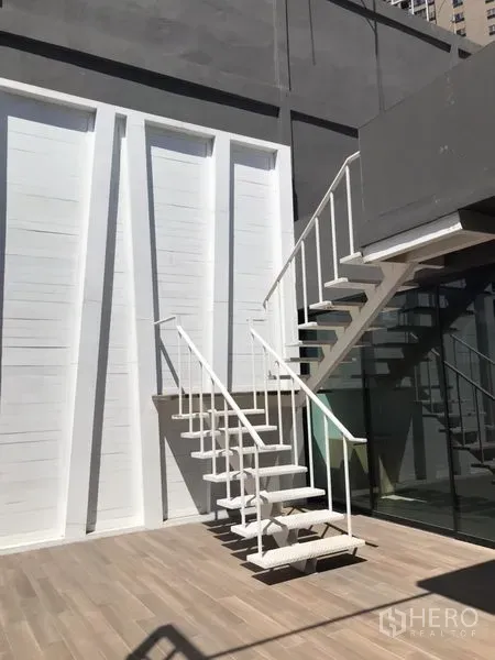 พื้นที่ขายปลีก ให้เช่าในKhlong Toei, Bangkok - คอร์ตด้านนอกพร้อมบันไดเหล็กสีขาวและผนังกระจก เชื่อมสู่ชั้นบนของยูนิต