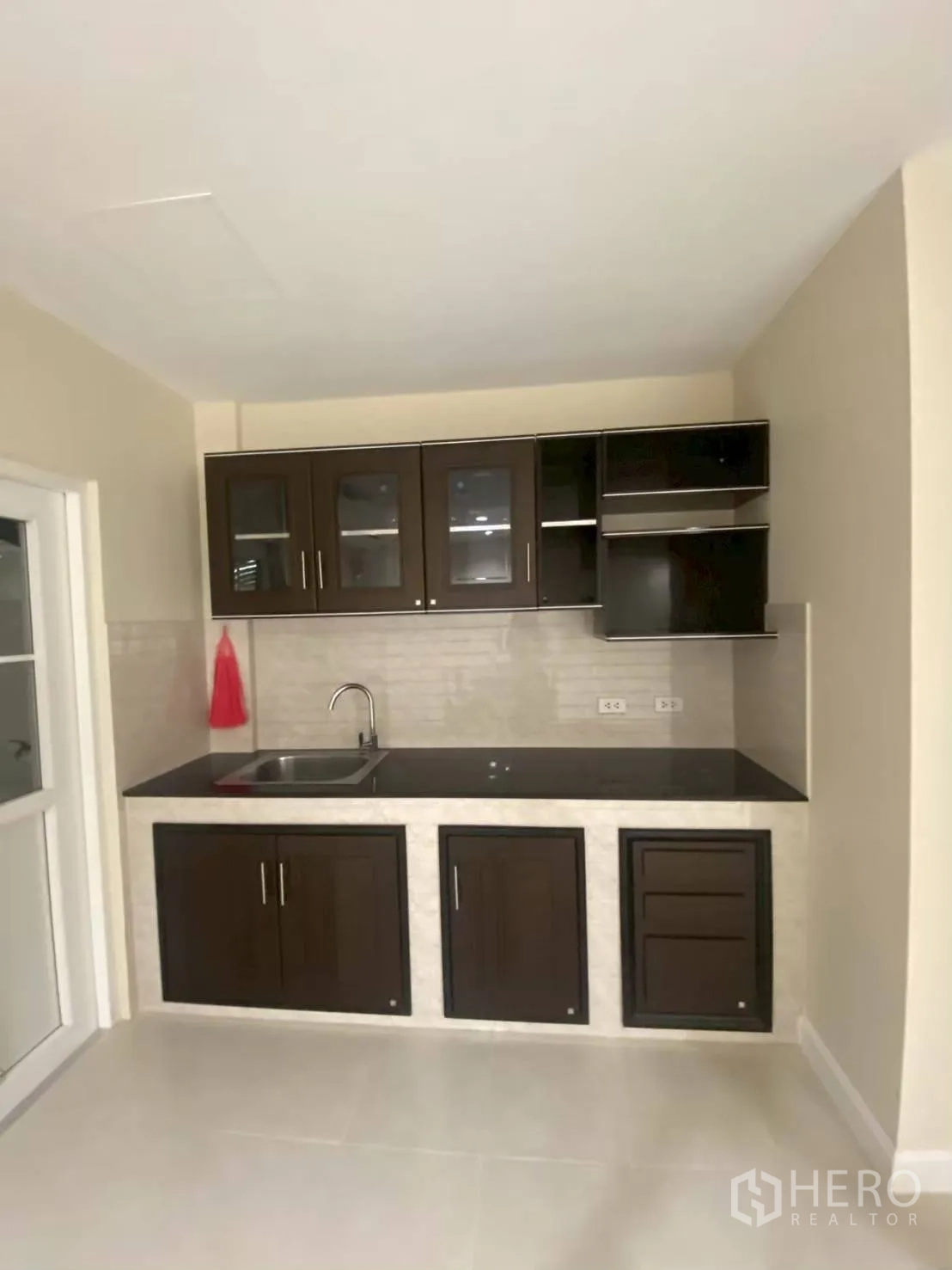 Townhouse for rent in Bang Kapi, Bangkok - Compact kitchen with dark cabinets, sink, and backsplash.