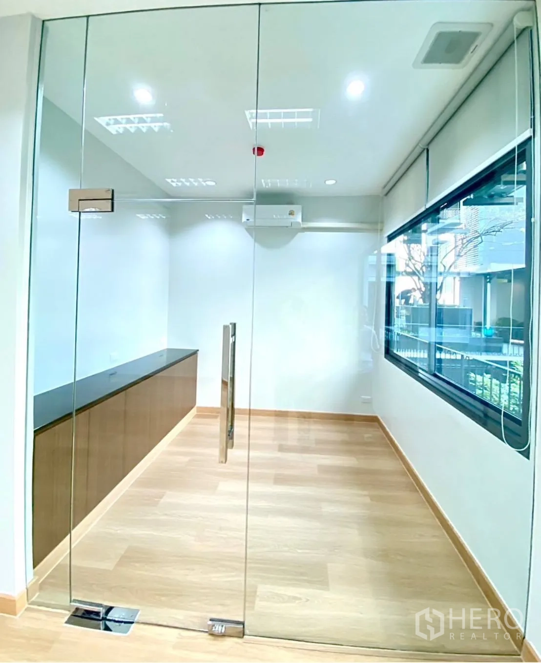 Office Space for rent - Compact glass meeting room with long cabinet and window view.