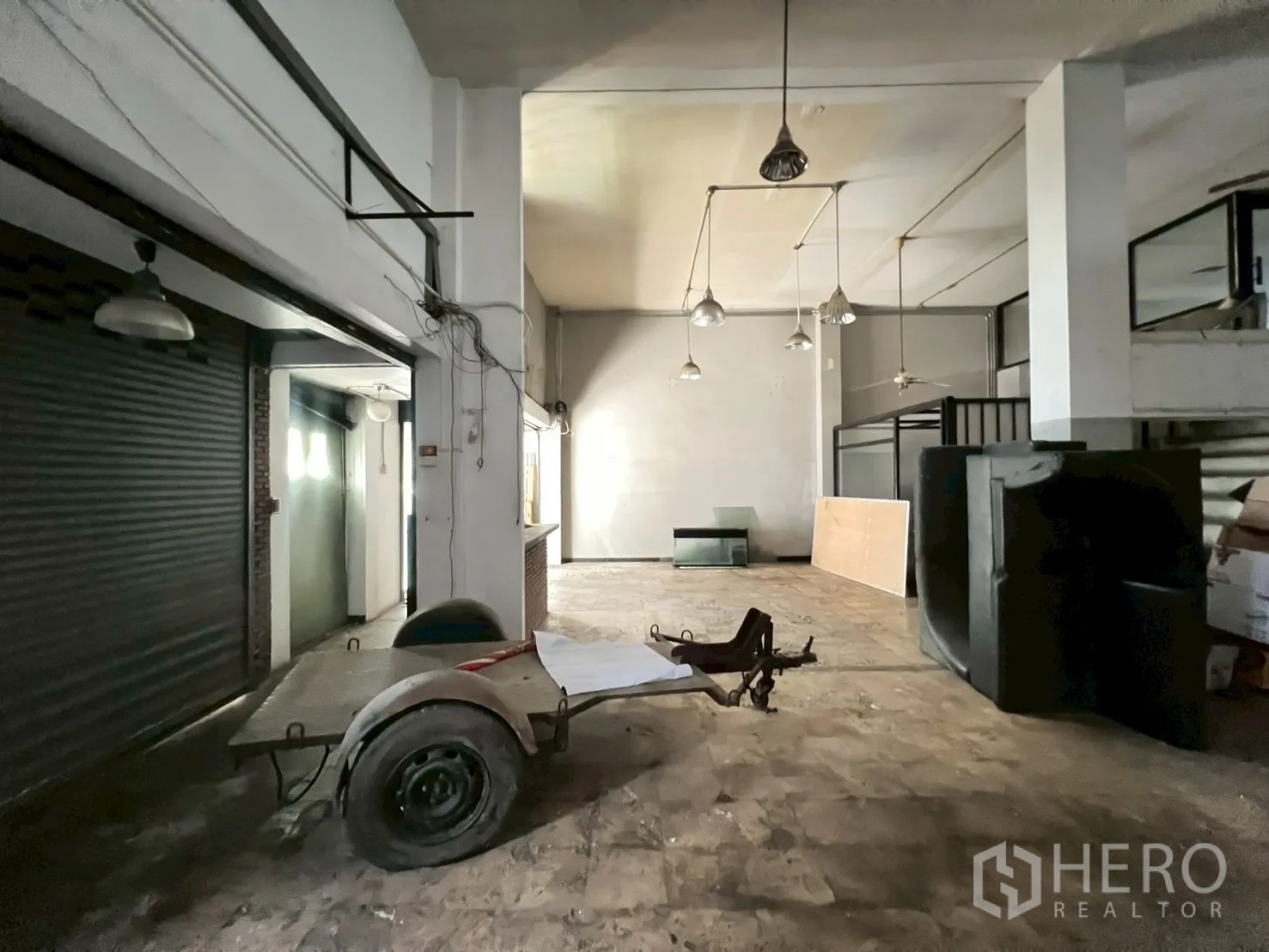 店屋 出租在Phra Khanong, Bangkok - 开放式仓库风格楼层，吊灯与金属卷闸门。