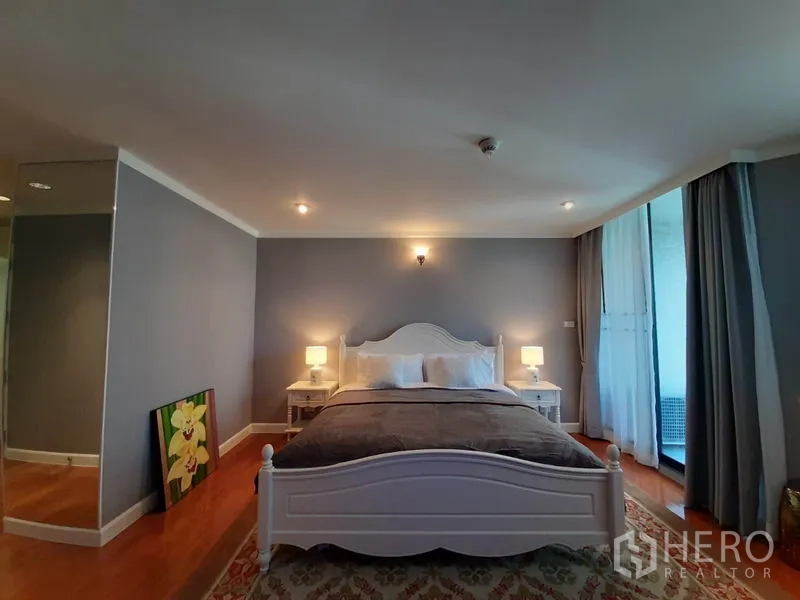 公寓 出租或出售在Watthana, Bangkok - 宽敞主卧，白色床架、床头灯及通往阳台的推拉门。