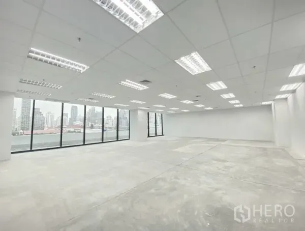 สำนักงาน ให้เช่าในRatchathewi, Bangkok - ภายในสำนักงานแบบเปิดโล่ง ฝ้าเพดานกริด ไฟ LED พื้นคอนกรีต และหน้าต่างบานใหญ่เห็นวิวเมือง