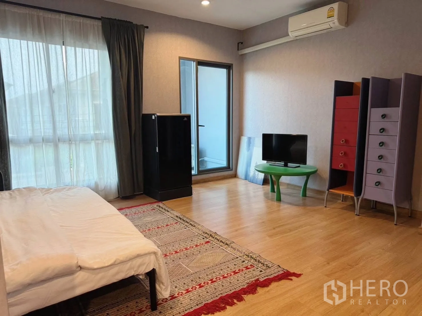 Detached House for rent or sale in Suan Luang, Bangkok - Spacious bedroom with wood flooring, balcony door, air conditioner and cabinets.