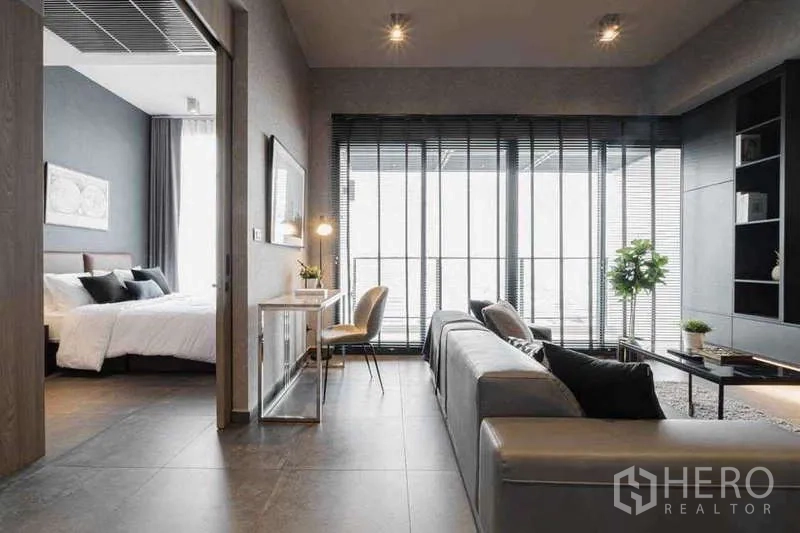 Condominium for rent in Watthana, Bangkok - Loft-style lounge with work desk, sofa and full-height windows beside the bedroom.