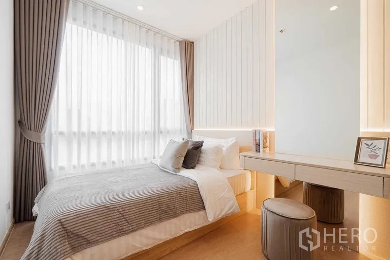Condominium for rent in Watthana, Bangkok - Second bedroom with large window, built-in dressing table and soft lighting.