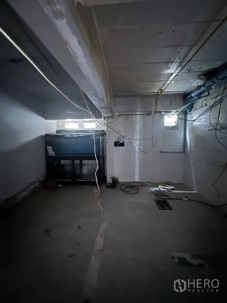 零售空间 出租在Watthana, Bangkok - 后勤机房，外露管线与布线，设小窗与混凝土地面。