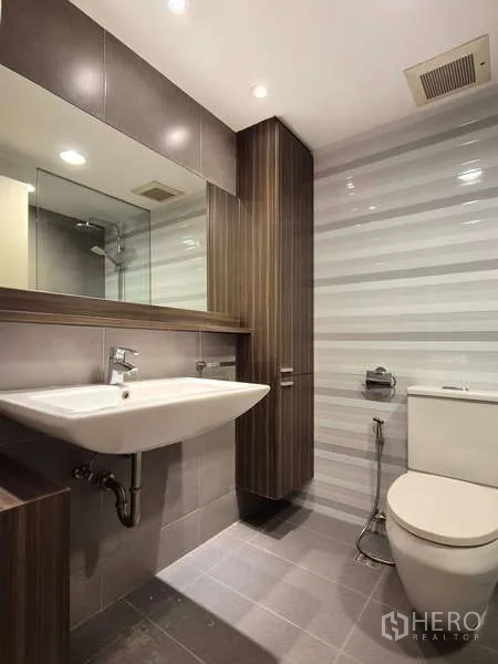 Condominium for rent in Yan Nawa, Bangkok - Second bathroom with wall cabinet, large mirror and striped tile wall.