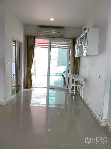 联排别墅 出租或出售在Wang Thonglang, Bangkok - 开放式起居区，装有空调，推拉门通往半户外空间，墙柜与白色书桌一体。