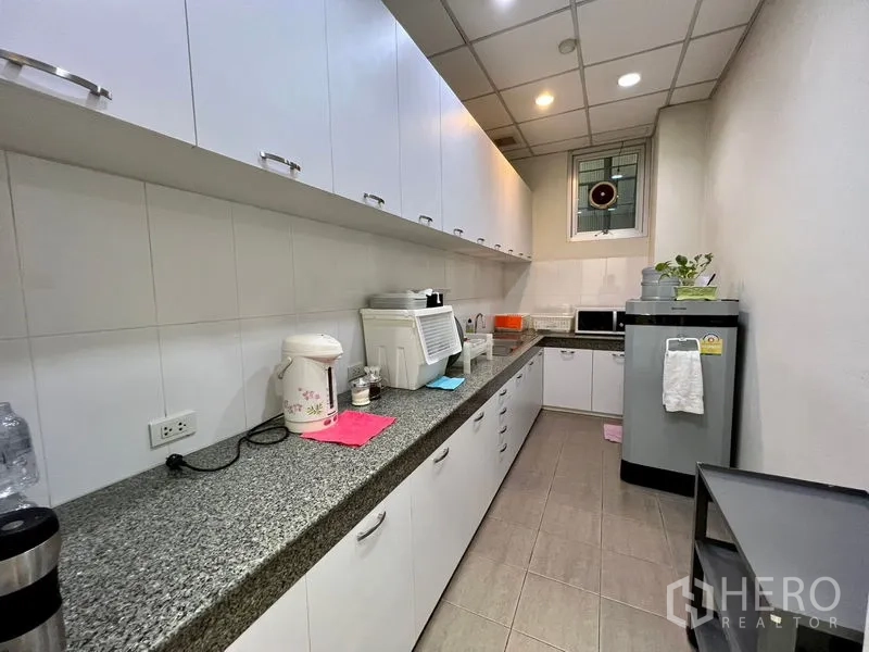 Office Space for rent in Bueng Kum, Bangkok - Pantry kitchenette with long granite countertop, white cabinets, microwave and refrigerator.