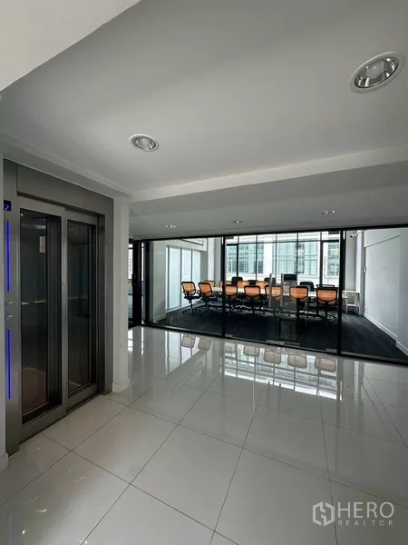 Home Office for rent - Elevator lobby with glossy tiles facing a glass-walled meeting room.