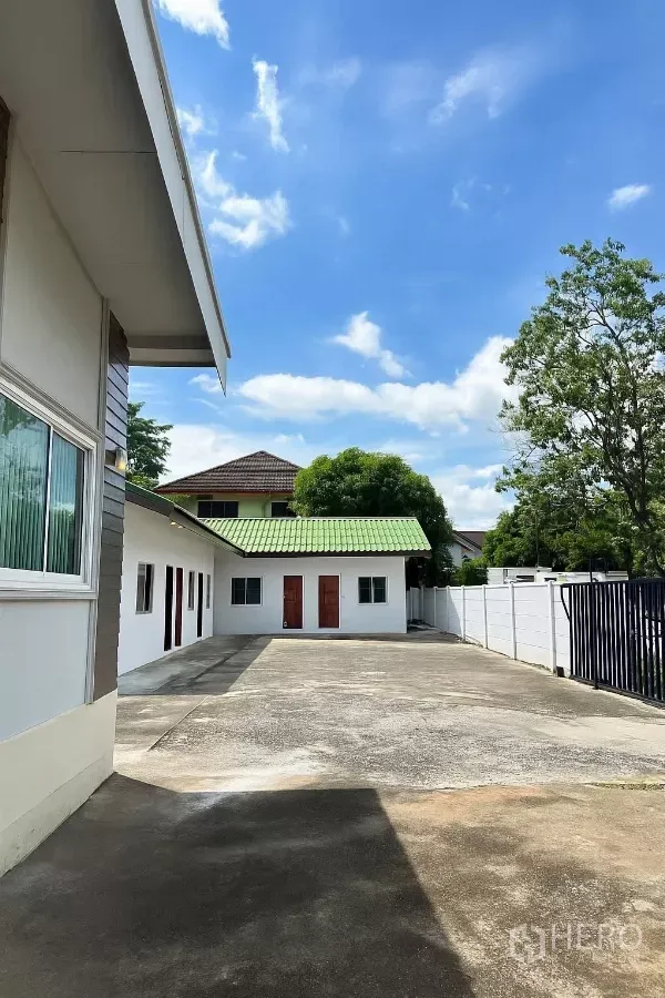 Home Office for rent in Bang Phli, Samut Prakan - Gated concrete courtyard with single-storey home office blocks and a green roof under a bright blue sky.