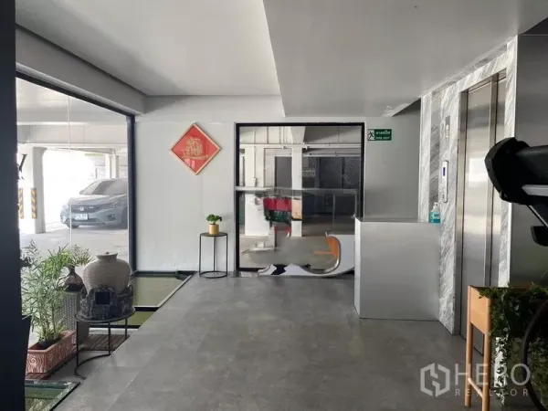 Office Space for rent or sale in Suan Luang, Bangkok - Ground-floor lobby with elevator, compact reception counter and indoor plants beside the parking area.