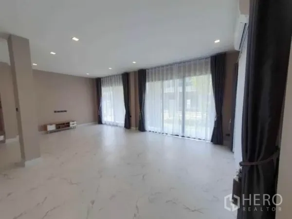 Detached House for rent in Lak Si, Bangkok - Bright living room with floor-to-ceiling windows, sheer curtains, recessed lights and marble-look floors.