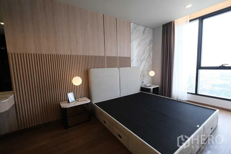 คอนโด ให้เช่าในKhlong Toei, Bangkok - ห้องนอนใหญ่ ผนังไม้เซาะร่อง หัวเตียงบุนวม และหน้าต่างวิวเมือง