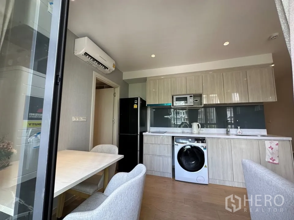 公寓 for rent in Watthana, Bangkok - 餐桌靠近推拉门，旁为厨房，配冰箱、微波炉与洗衣机。