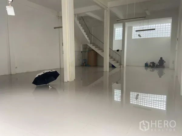 Shophouse for rent in Prawet, Bangkok - Spacious ground-floor open plan of the shophouse with glossy tiled floors, white columns and an internal staircase.