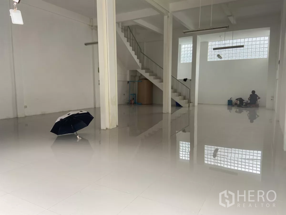 Shophouse for rent in Prawet, Bangkok - Spacious ground-floor open plan of the shophouse with glossy tiled floors, white columns and an internal staircase.