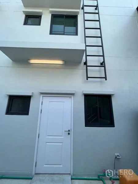 Home Office for rent - Rear facade showing a white service door, windows and an exterior metal ladder.