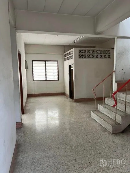 Factory for rent in Bang Na, Bangkok - Stairwell and landing area with a window and access to restrooms in the industrial facility.