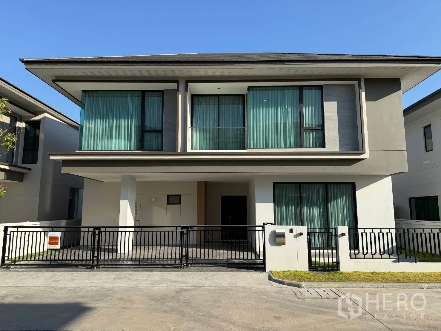 Detached House for rent in Bang Phli, Samut Prakan - Modern two-storey detached house with wide windows, balcony, and a black metal gate.