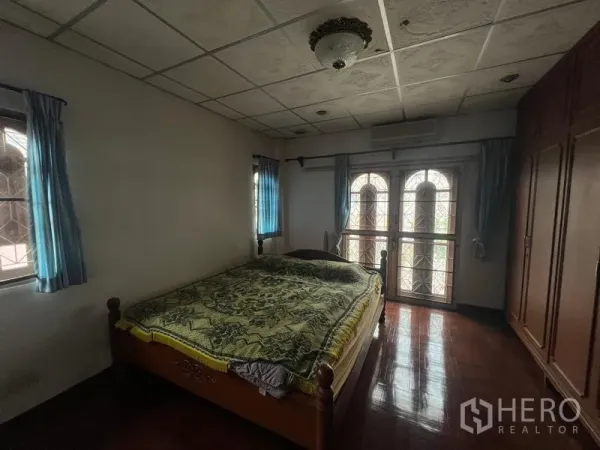 บ้าน ขายในPhra Khanong, Bangkok - ห้องนอนพื้นไม้ มีประตูกระจกโค้งออกสู่ระเบียง หน้าต่าง และตู้เสื้อผ้าบิวท์อิน