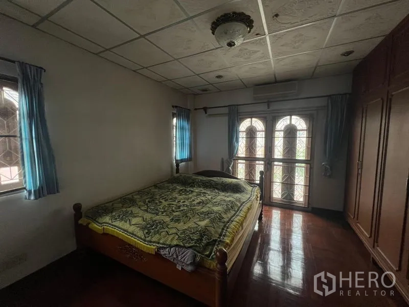 บ้าน ขายในPhra Khanong, Bangkok - ห้องนอนพื้นไม้ มีประตูกระจกโค้งออกสู่ระเบียง หน้าต่าง และตู้เสื้อผ้าบิวท์อิน