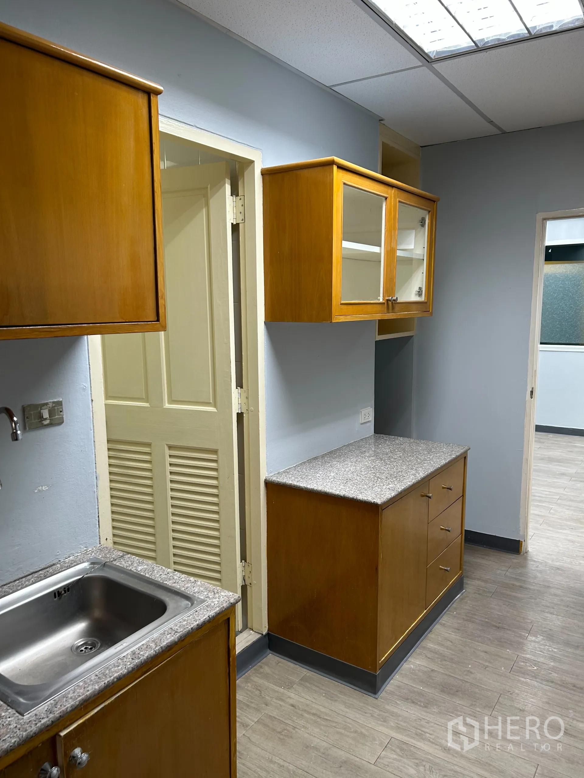 办公空间 出租在Khlong Toei, Bangkok - 茶水间细节：上下木柜与仿石台面，照明明亮。