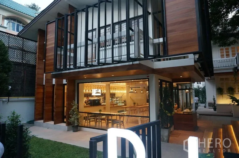 พื้นที่ขายปลีก ให้เช่าในBang Rak, Bangkok - มุมมองยามเย็นของหน้าร้านกระจก แสงไฟอบอุ่น พร้อมพื้นที่นั่งด้านนอกและทางเข้าแต่งสวนในย่านสีลม