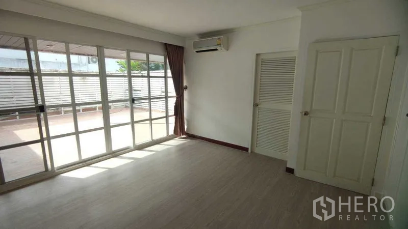 Home Office for rent in Watthana, Bangkok - Bright bedroom with floor-to-ceiling sliding doors opening to a spacious terrace.