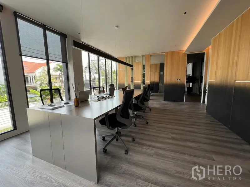 Home Office for sale in Prawet, Bangkok - Open-plan workspace with long desks, ergonomic chairs, and floor-to-ceiling windows.