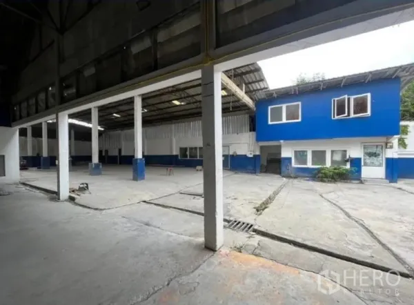 คลังสินค้า ให้เช่าในPhra Khanong, Bangkok - โกดังแบบโปร่งเสากลางสูง ลานคอนกรีต พร้อมออฟฟิศสองชั้นสีน้ำเงิน‑ขาว