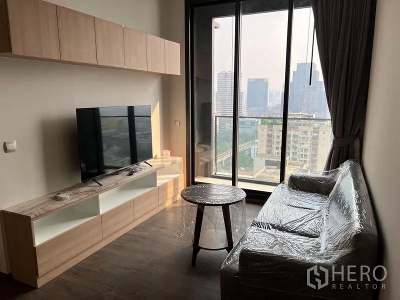 คอนโด ให้เช่าในRatchathewi, Bangkok - ห้องนั่งเล่นกะทัดรัด มีตู้ทีวี โซฟา และทางออกสู่ระเบียงพร้อมวิวเมือง