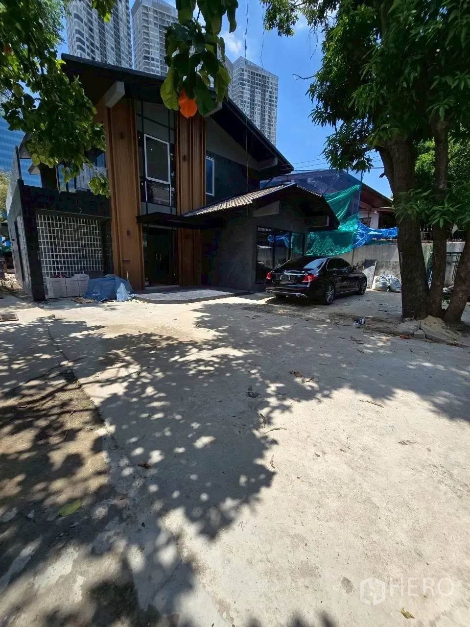 Detached House for rent in Phra Khanong, Bangkok - Spacious front yard with driveway parking and shade trees before the house.