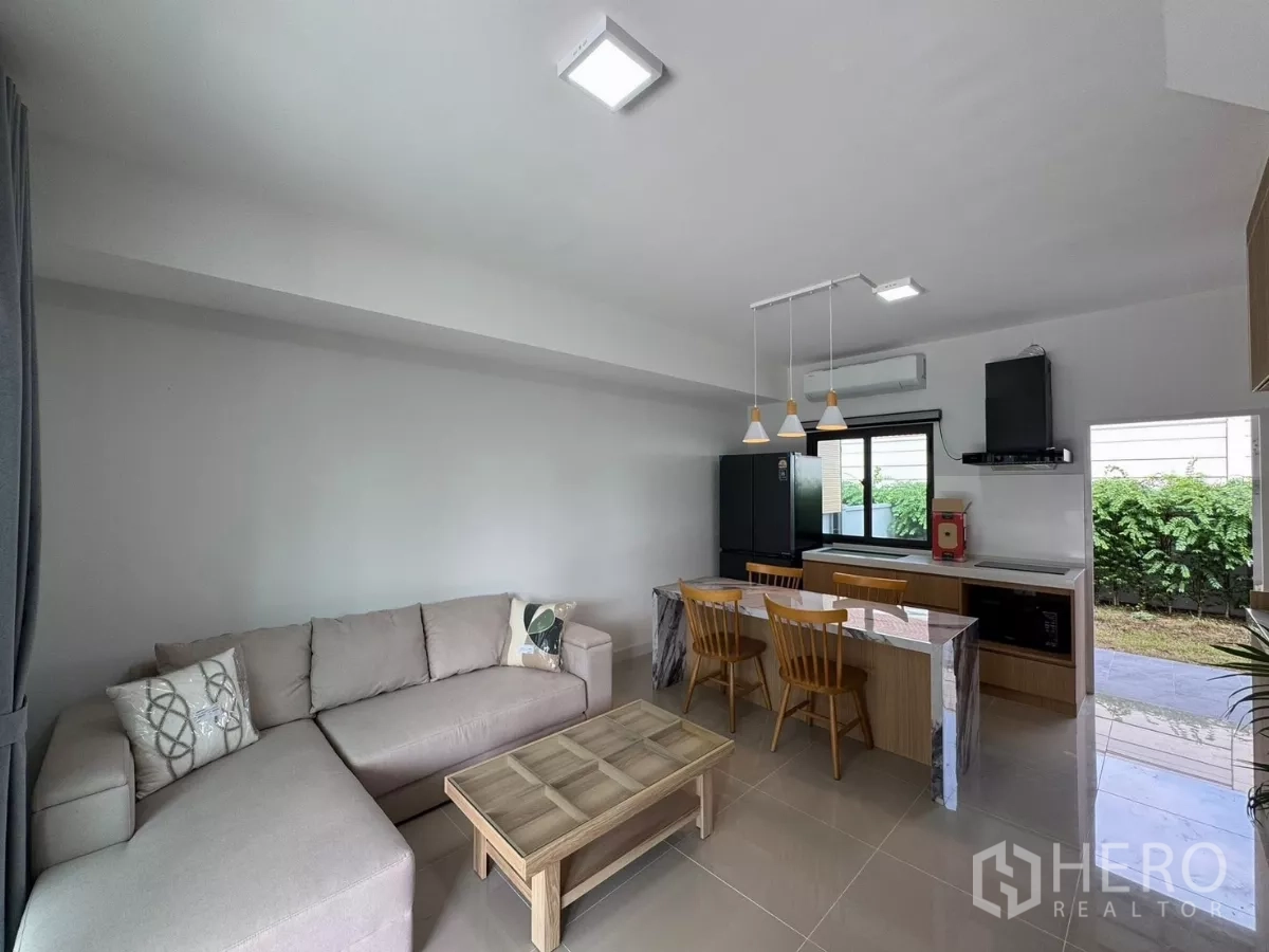 ทาวน์เฮาส์ ให้เช่าในBang Phli, Samut Prakan - พื้นที่นั่งเล่น รับประทานอาหาร และครัวแบบเปิด พร้อมโซฟาเข้ามุมและวิวสวน