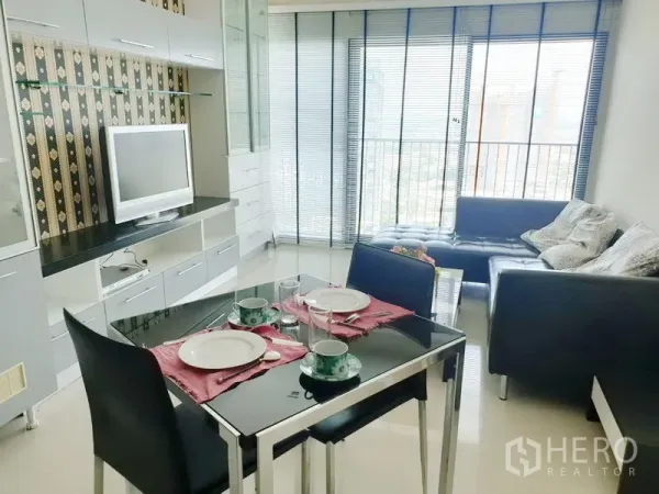 公寓 出租在Khlong Toei, Bangkok - 明亮的客餐厅，带电视柜、玻璃餐桌、皮沙发和带百叶的城市景观阳台。