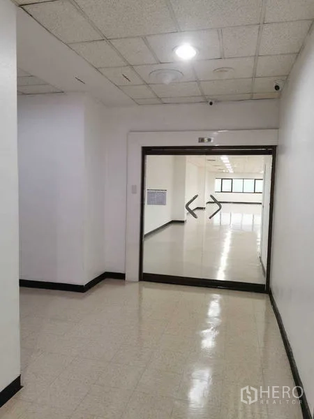 办公空间 出租在Watthana, Bangkok - 通往办公室的走廊，双开玻璃门与监控摄像头。