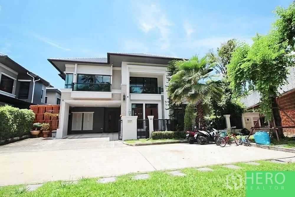 Detached House for rent in Bang Khae, Bangkok - Two-storey detached house exterior with wide driveway, balcony glass railings and lush front garden in Bang Khae.