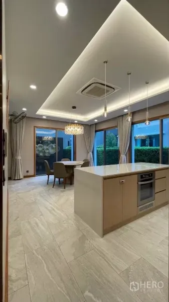 Detached House for rent in Prawet, Bangkok - Open kitchen with island, pendant lights, built-in oven and garden views.